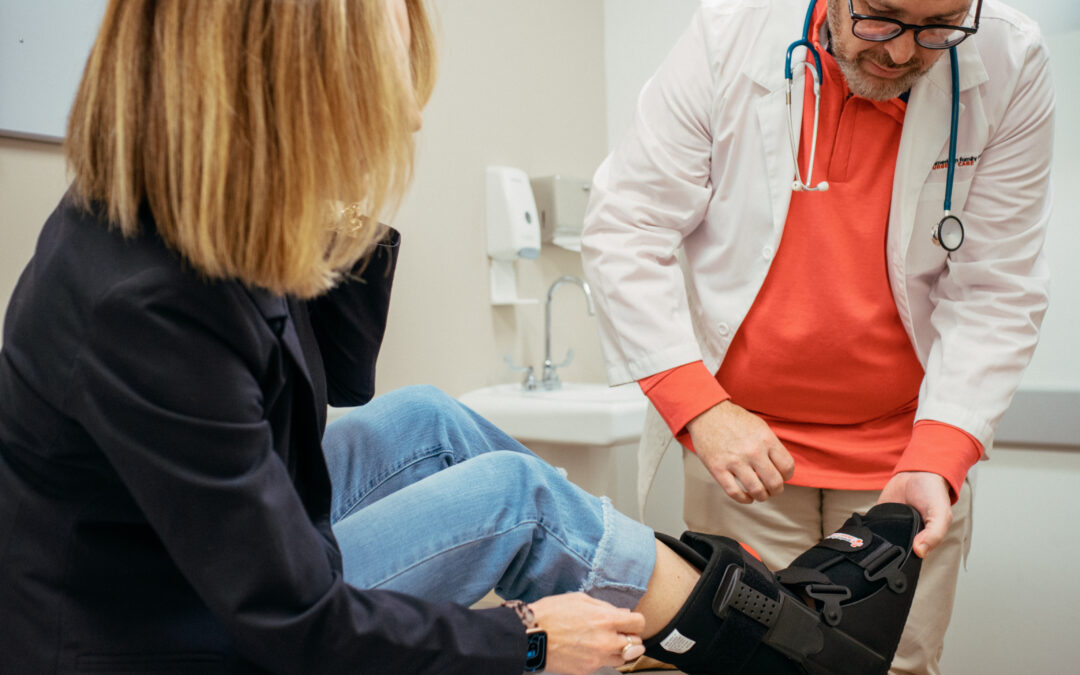Male AFC healthcare provider helping a patient place a walking boot on her right foot after injury.